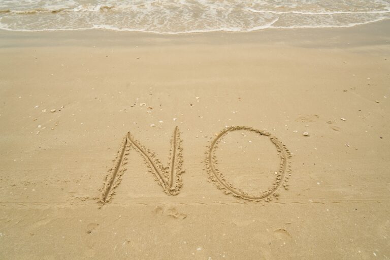 Image of a beach, where somebody wrote "no" in the sand.